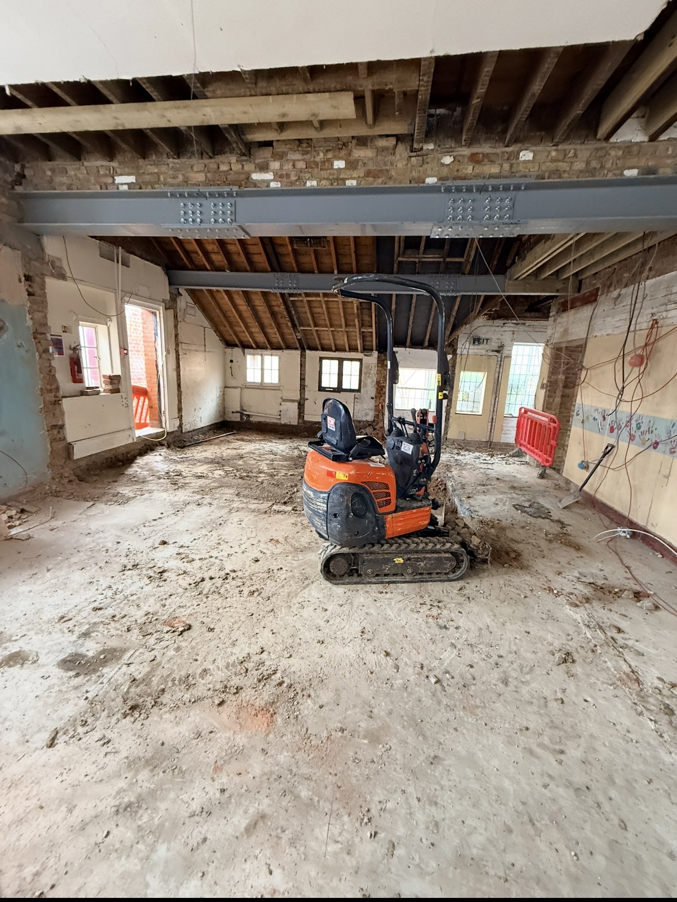 Mini excavator carrying out internal excavation beneath the new steel beams at Bishop Stortford