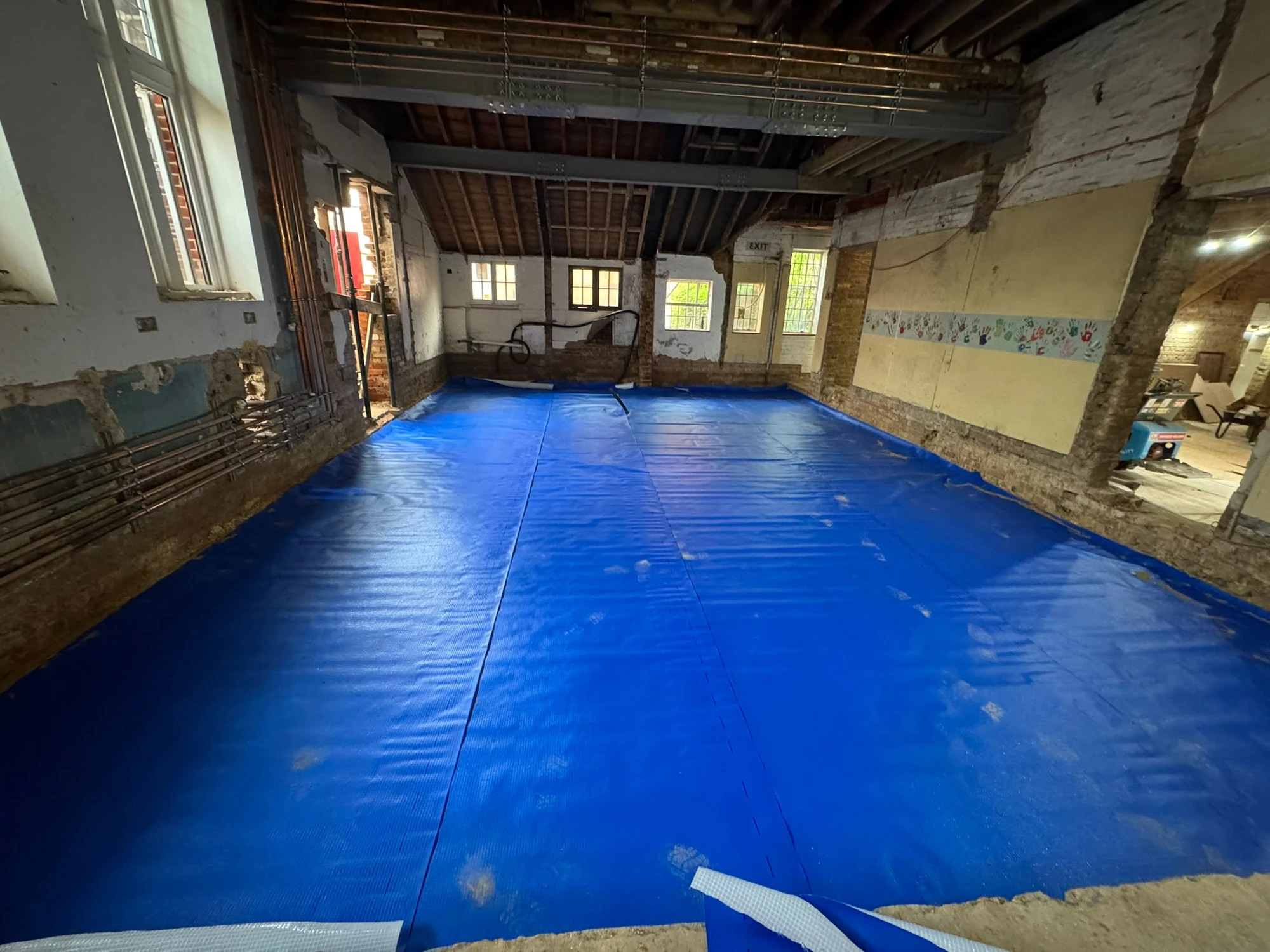 Blue damp-proof membrane laid across the hall floor at Bishop Stortford