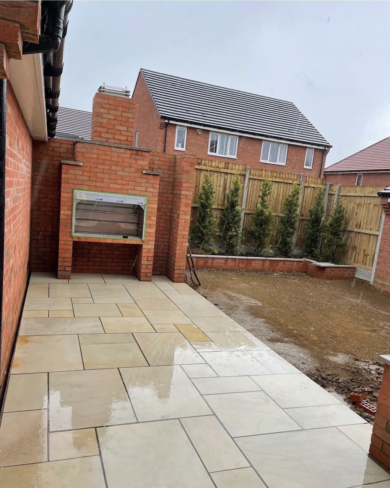 Completed sawn sandstone patio with bespoke brick BBQ and raised planters at Buckton Fields