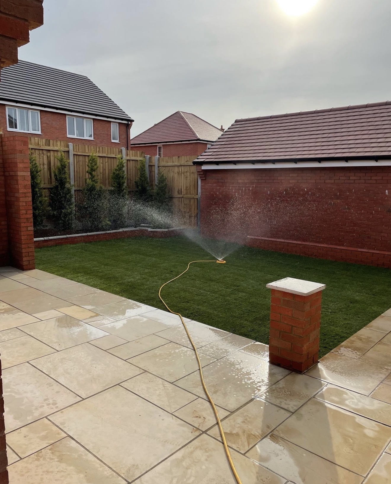 Newly laid lawn being watered in beside the sandstone patio at Buckton Fields