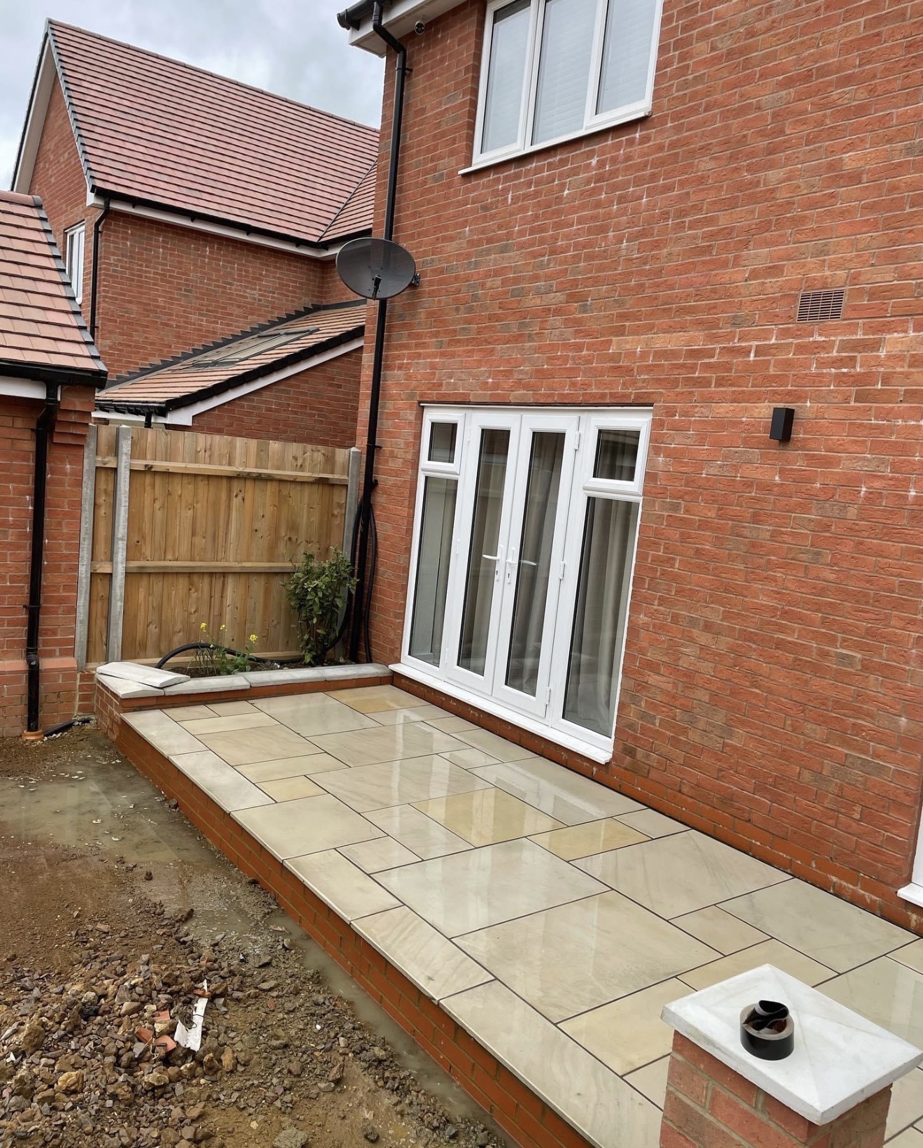 Sawn sandstone patio with raised brick planter outside the French doors at Buckton Fields